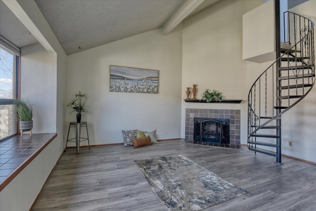 living area with stairway, a tile fireplace, wood finished floors, and baseboards