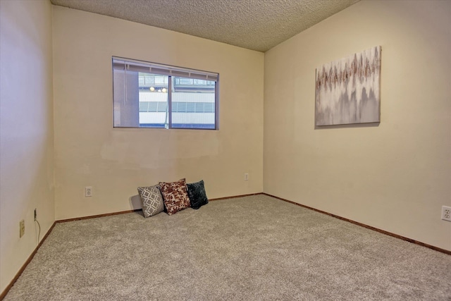 carpeted empty room with a textured ceiling and baseboards