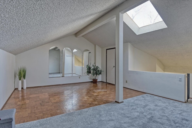 additional living space with a textured ceiling, lofted ceiling with skylight, and baseboards