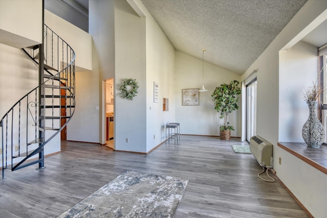 entrance foyer featuring baseboards, wood finished floors, stairs, a textured ceiling, and high vaulted ceiling