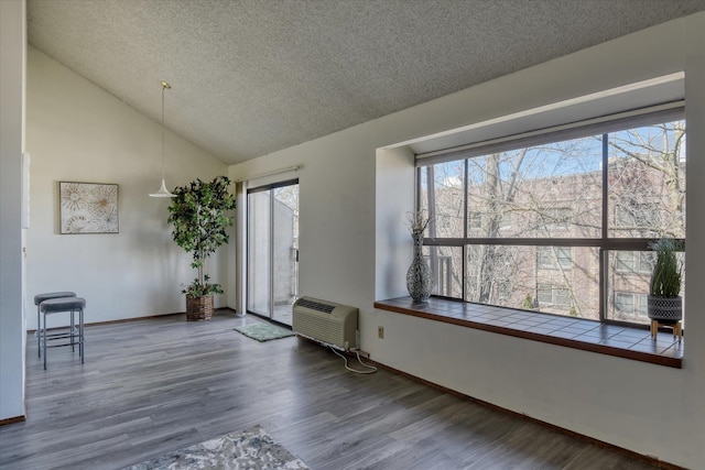 unfurnished room featuring lofted ceiling, a textured ceiling, wood finished floors, and baseboards