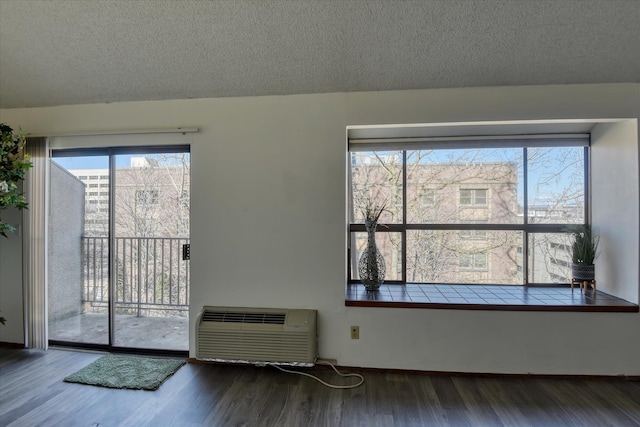 unfurnished room featuring a textured ceiling, wood finished floors, and a wall mounted AC