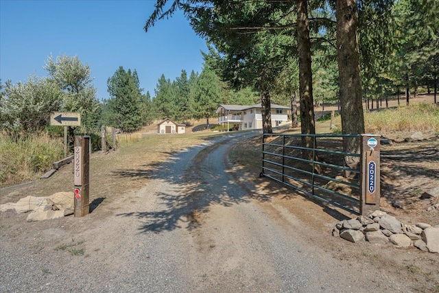 view of road with dirt driveway, a gated entry, and a gate