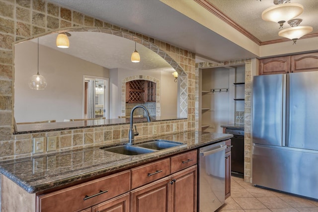 kitchen with brown cabinets, stainless steel appliances, light tile patterned flooring, a sink, and a textured ceiling