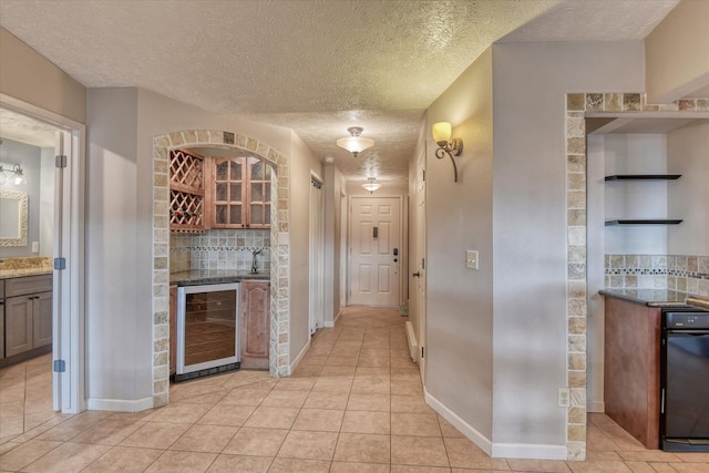 kitchen with light tile patterned floors, wine cooler, open shelves, and a textured ceiling