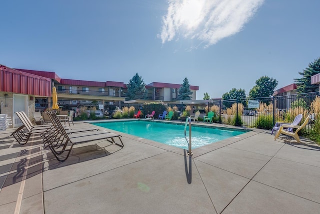 community pool with a patio and fence