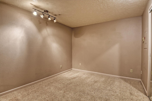 spare room with a textured ceiling, carpet floors, and baseboards