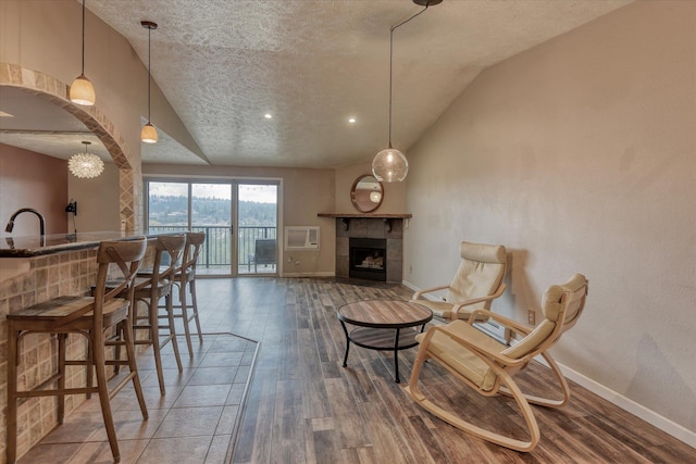 interior space featuring baseboards, vaulted ceiling, a tiled fireplace, and wood finished floors