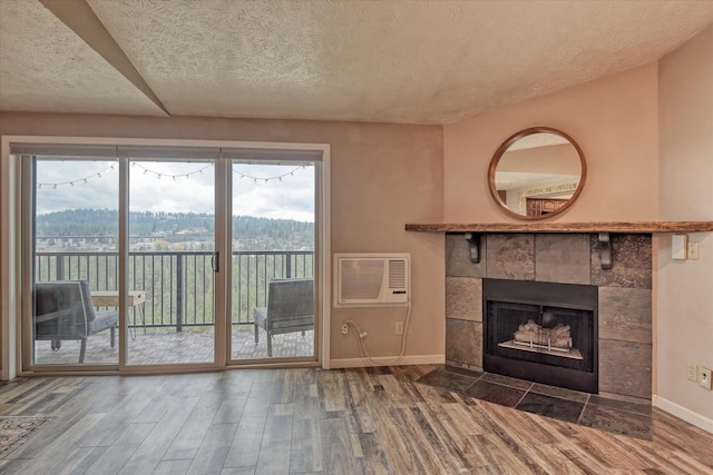 unfurnished living room with baseboards, a textured ceiling, a tiled fireplace, and wood finished floors