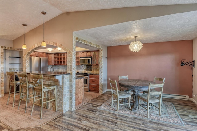 kitchen with dark countertops, a breakfast bar, brown cabinets, stainless steel appliances, and open shelves