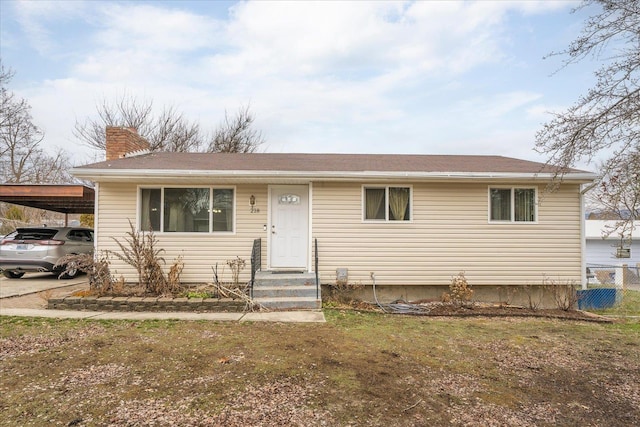 view of front facade with an attached carport, a chimney, a front lawn, and fence