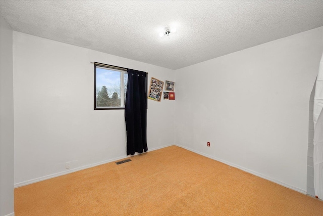 spare room featuring baseboards, visible vents, a textured ceiling, and light colored carpet