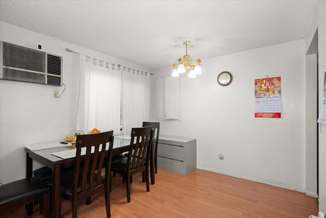 dining space with light wood-style flooring, a textured ceiling, baseboards, and a notable chandelier