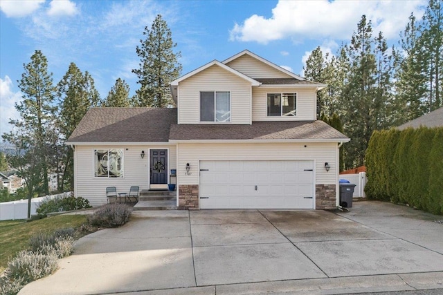 view of front facade with stone siding, an attached garage, fence, and driveway