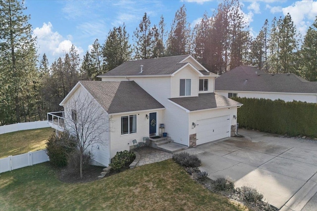 traditional-style house with an attached garage, fence, concrete driveway, roof with shingles, and a front yard