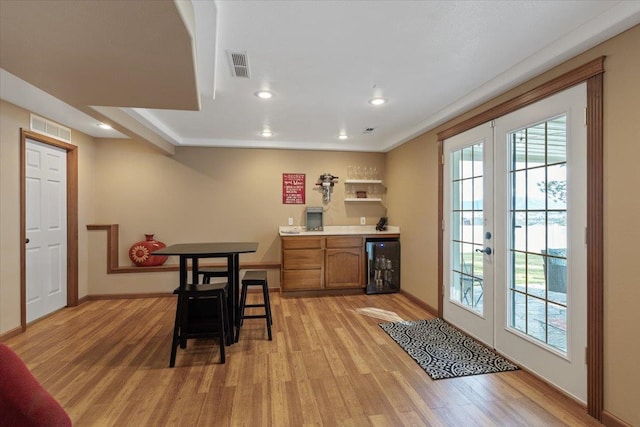 dining area featuring light wood-type flooring, wine cooler, visible vents, and french doors