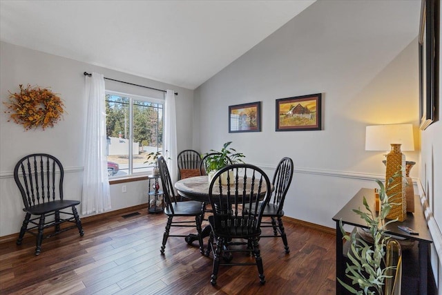 dining space featuring dark wood-style floors, visible vents, vaulted ceiling, and baseboards