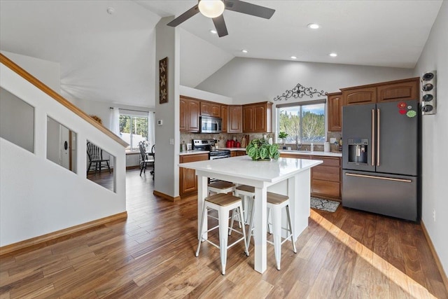 kitchen featuring a breakfast bar, light countertops, appliances with stainless steel finishes, wood finished floors, and plenty of natural light