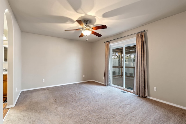 empty room with carpet floors, visible vents, baseboards, and a ceiling fan