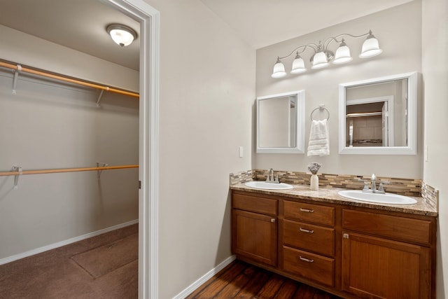 full bathroom with a sink, a spacious closet, baseboards, and double vanity