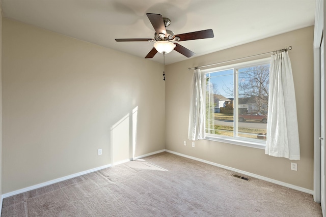 spare room with visible vents, carpet floors, a ceiling fan, and baseboards