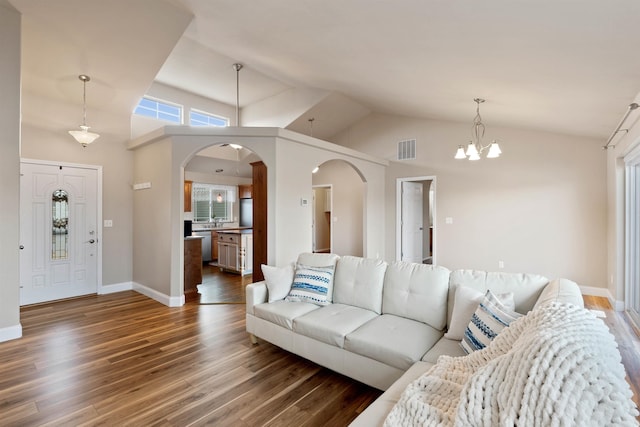 living area featuring arched walkways, visible vents, an inviting chandelier, wood finished floors, and baseboards