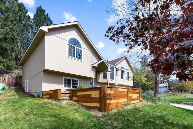 back of property with fence and a lawn