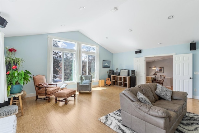 living area featuring lofted ceiling, wood finished floors, and baseboards