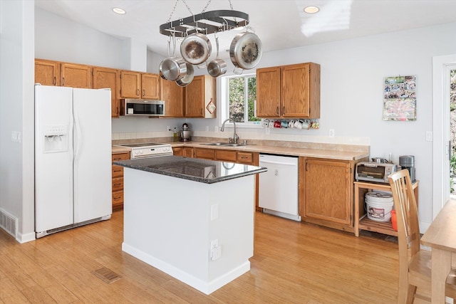 kitchen with white appliances, light wood-type flooring, a sink, and recessed lighting