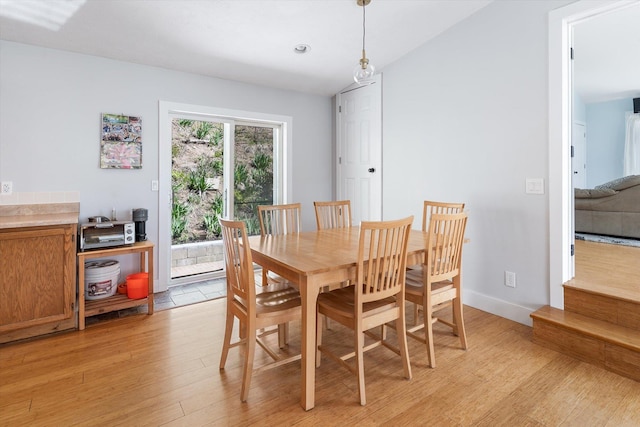 dining room with baseboards, vaulted ceiling, recessed lighting, and light wood-style floors