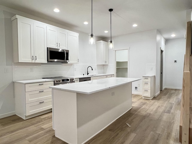 kitchen with tasteful backsplash, appliances with stainless steel finishes, light wood-style floors, white cabinetry, and a sink