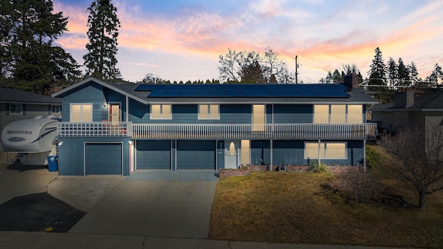 view of front facade with a garage, solar panels, and concrete driveway