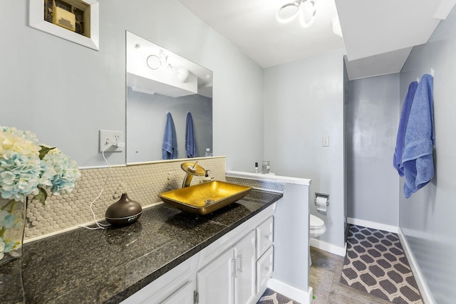 bathroom with tasteful backsplash, toilet, vanity, and baseboards