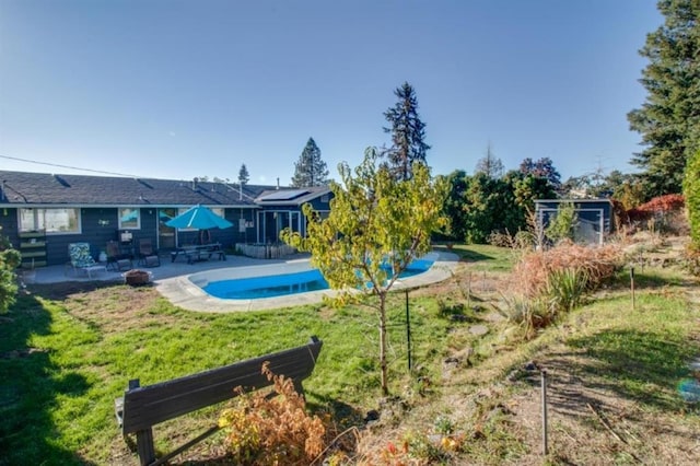 back of property with a yard, an outdoor pool, and a patio