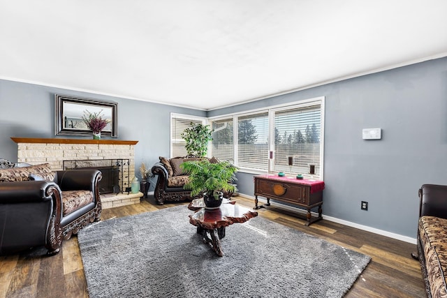 living area with a brick fireplace, baseboards, and wood finished floors