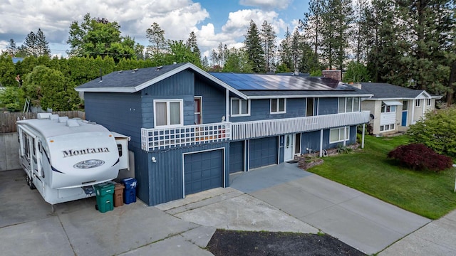6514 N Sutherlin St, Spokane, WA 99208 - view of front of home with concrete driveway, a front yard, a chimney, solar panels, and an attached garage