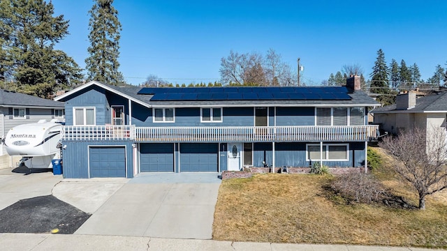 view of front of home with roof mounted solar panels, driveway, a front lawn, and an attached garage