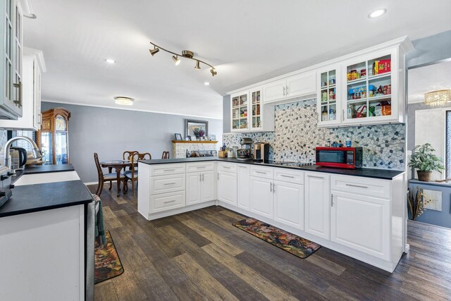 kitchen featuring dark wood-type flooring, dark countertops, white cabinetry, and a peninsula