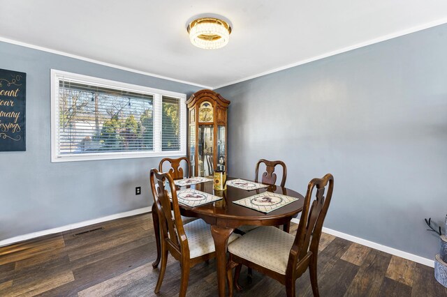 dining space featuring dark wood-style floors, crown molding, visible vents, and baseboards