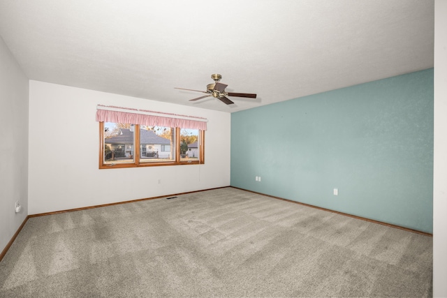 spare room with carpet floors, a ceiling fan, and baseboards