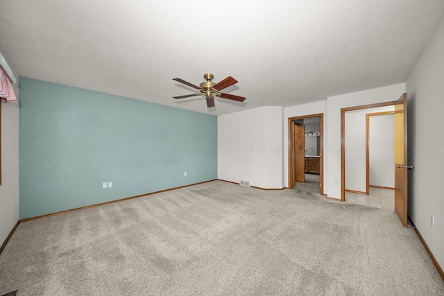 unfurnished bedroom featuring light carpet, ceiling fan, baseboards, and a textured ceiling