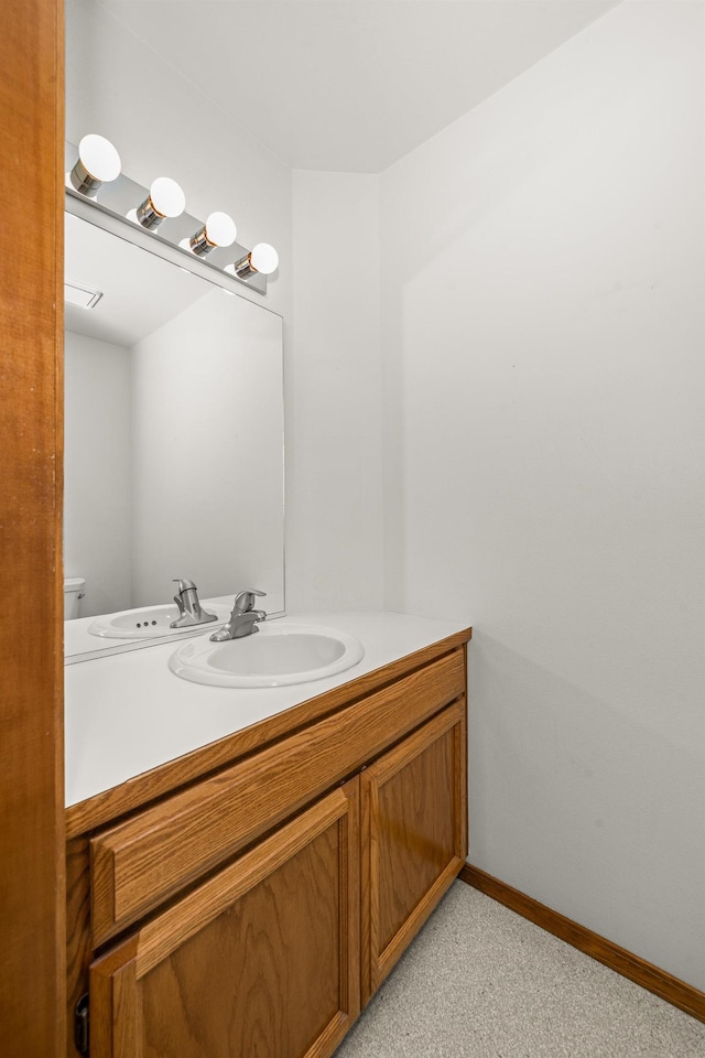 half bathroom with toilet, vanity, and baseboards