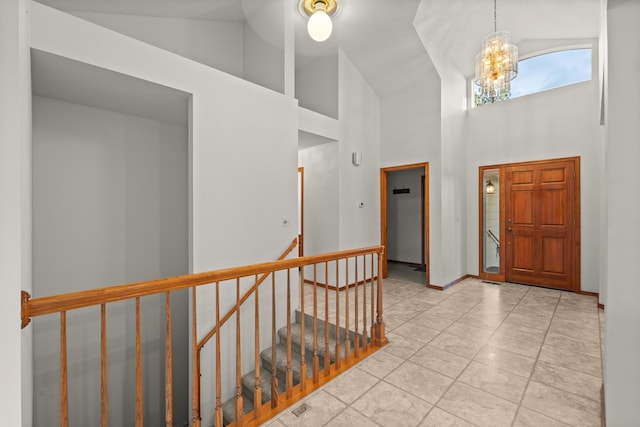 entryway with baseboards, high vaulted ceiling, and a notable chandelier