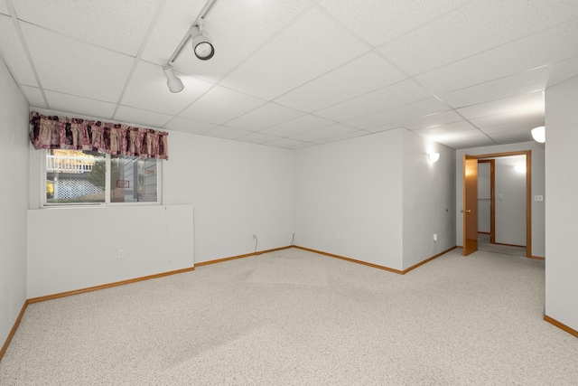 carpeted spare room featuring a paneled ceiling, rail lighting, and baseboards