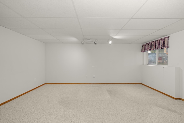 basement with track lighting, a paneled ceiling, baseboards, and carpet