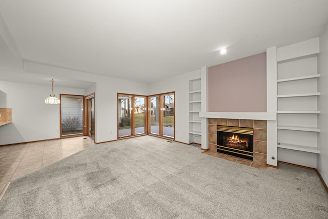 unfurnished living room with baseboards, carpet floors, a tiled fireplace, and built in features