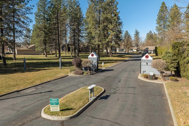 view of road featuring traffic signs, curbs, and a gated entry