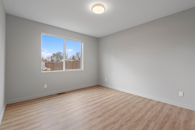 spare room featuring light wood-type flooring and baseboards