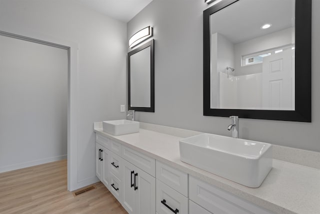 bathroom with double vanity, visible vents, a sink, and wood finished floors