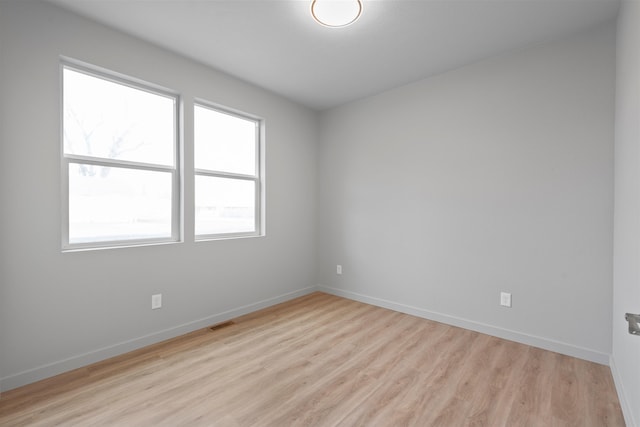 unfurnished room featuring visible vents, light wood-style flooring, and baseboards